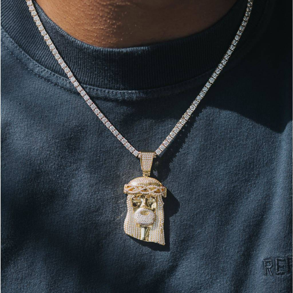 A person wearing a gold-colored necklace with a pendant featuring an image of Jesus Christ.