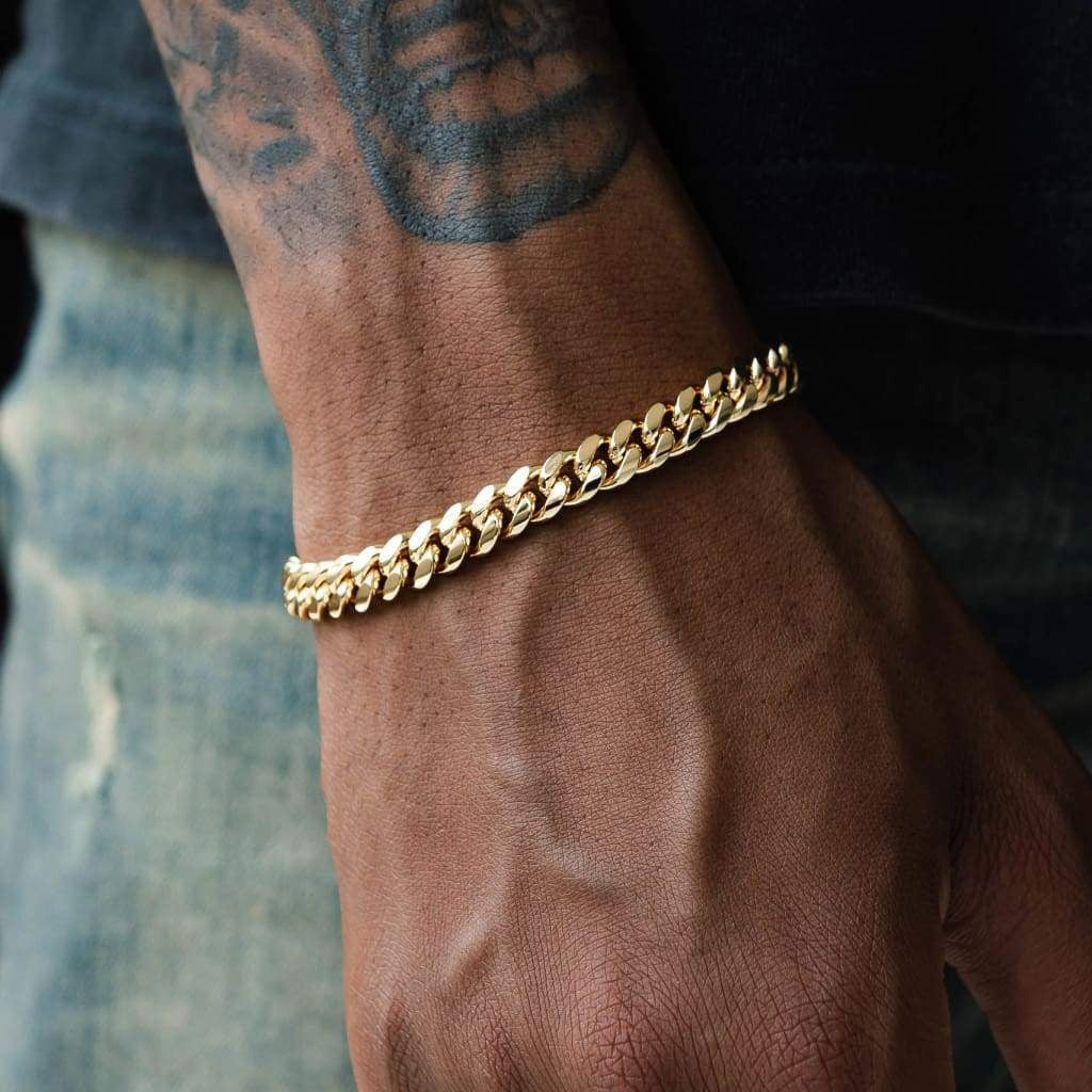 A person wearing a gold Miami Cuban link armband on their wrist.
