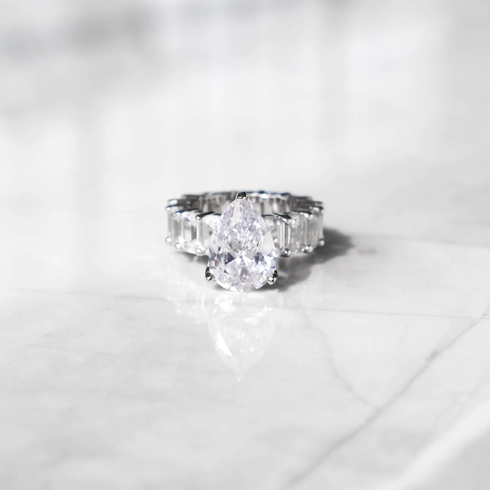A 14K white gold ring with a row of shimmering AAAA cubic zirconia stones set on a marble surface.
