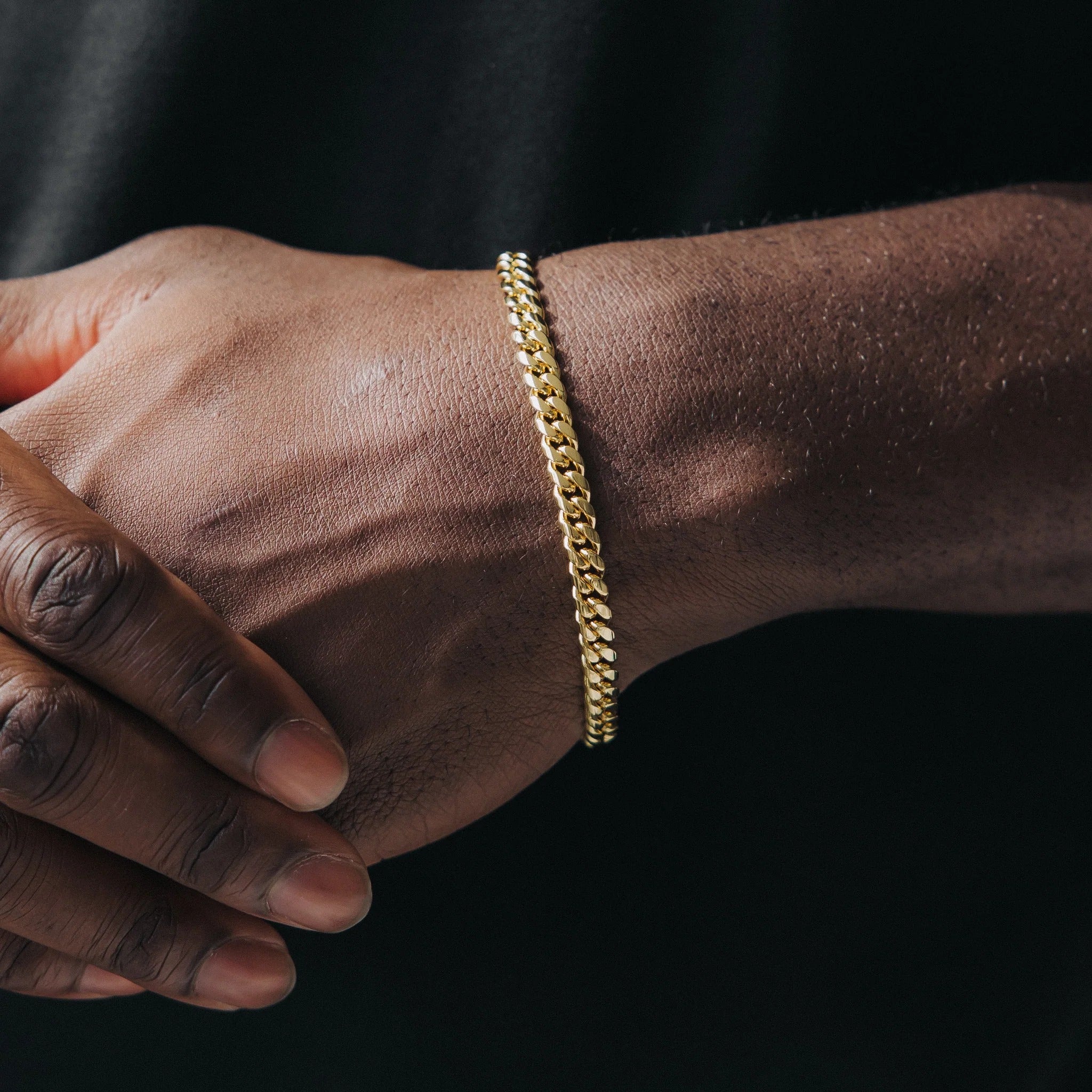 A person wearing a 6mm wide Miami Cuban gold armband/bracelet on their forearm.
