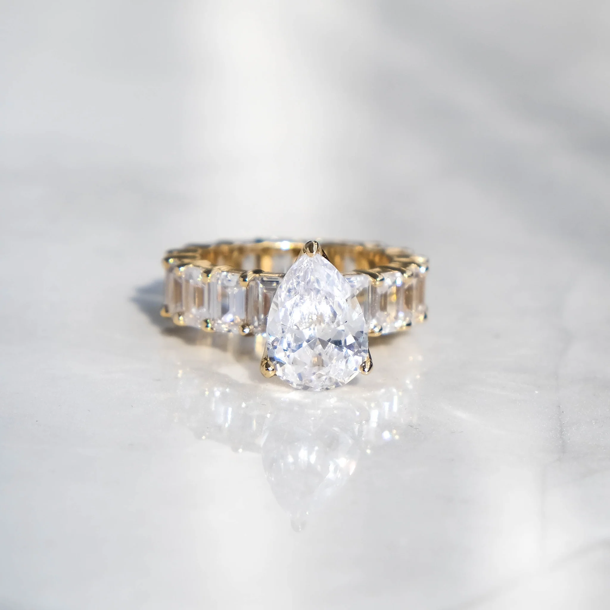 An 18K gold ring with a large central diamond surrounded by a band of smaller baguette cut diamonds