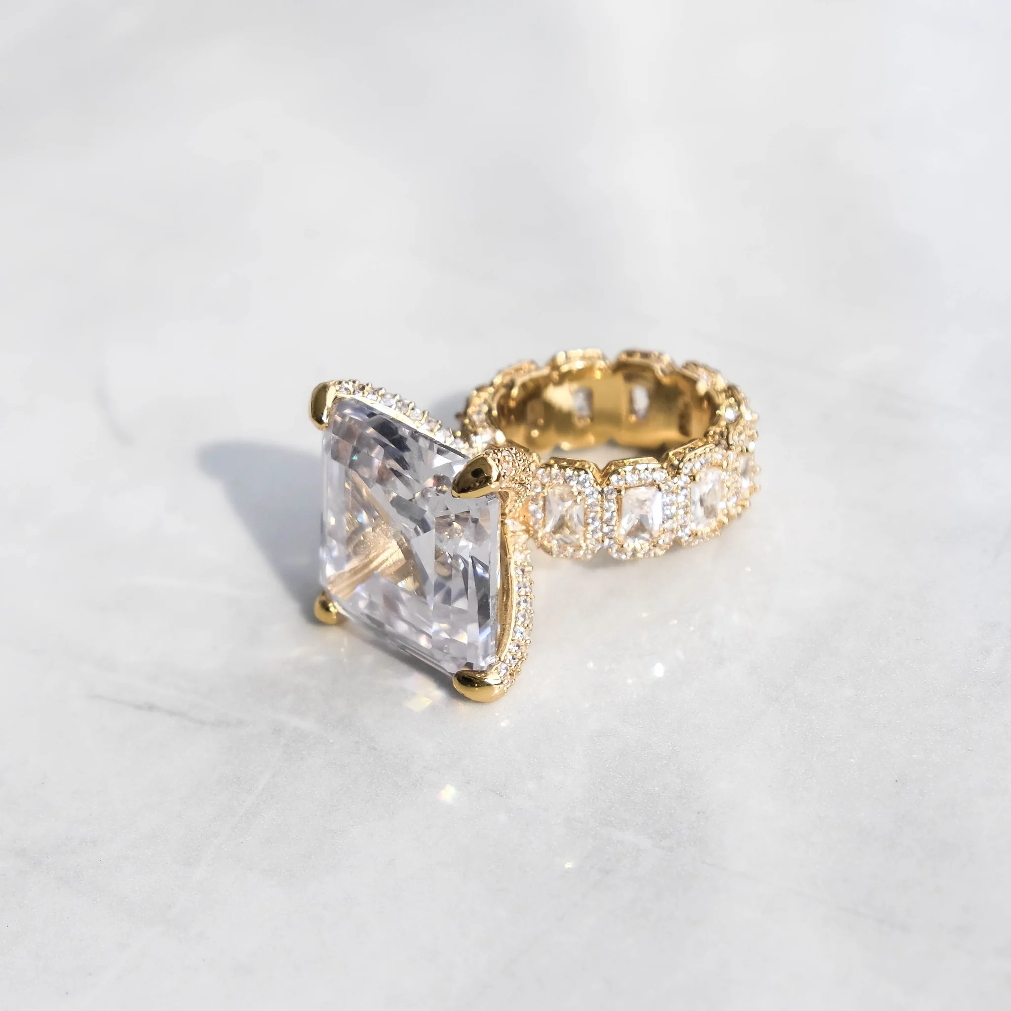 A white gold diamond ring with a large central diamond and smaller surrounding stones on a marble surface.